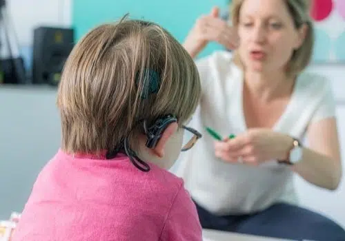 Educatrice échangeant avec un enfant malentendant doté d'un appareil auditif. Visuel utilisé pour illustrer le financement de projets oeuvrant pour l'inclusion scolaire