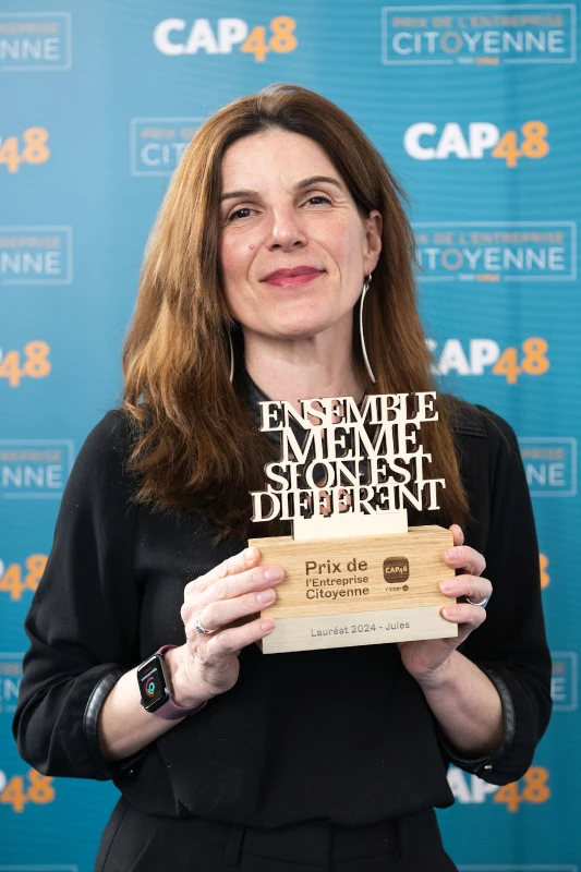 Une représentante de la marque Jules tient en mail le trophée du Prix Entreprise Citoyenne CAP48