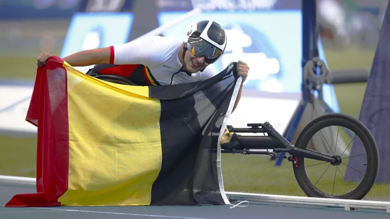 Maxime Carabin, athlète paralympique belge déploie le drapeau belge après une victoire