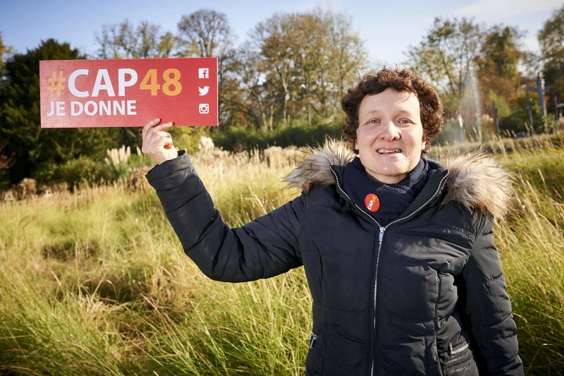 Une femme en parka tient un panneau qui dit 