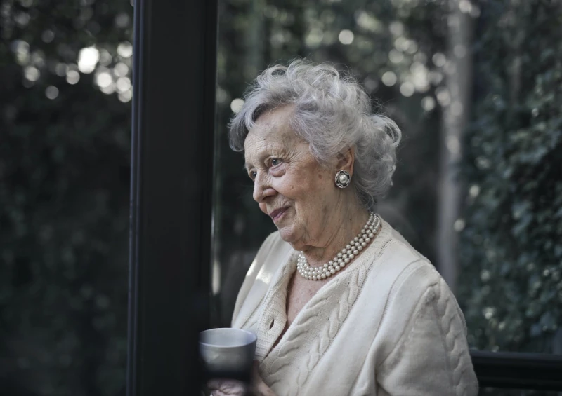 une dame d'un certain âge, elle porte un collier de perles