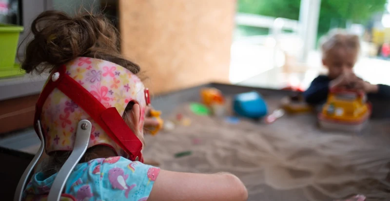 Deux jeunes enfants celui à l'avant-plan porte un casque d'aide thérapeutique