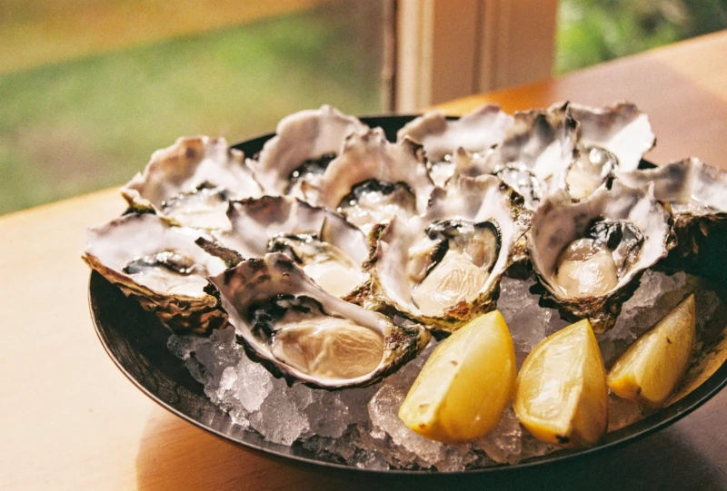 Une assiette d'huitres avec des quartiers de citron.